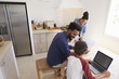 © Monkey Business - Parents helping kids with homework in kitchen, elevated view