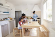 © Monkey Business - Dad sitting with kids at kitchen table while mum cooks