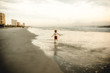© Samantha McBride - Rear view of boy running on beach