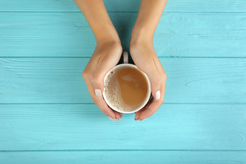 Canvas Print - Female hands holding cup of fresh coffee on wooden background