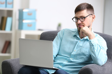 Handsome young programmer working with laptop at home