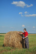 © sima - Farmer examine bale of hay in field