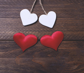 Two white hearts and two red hearts on brown wooden table