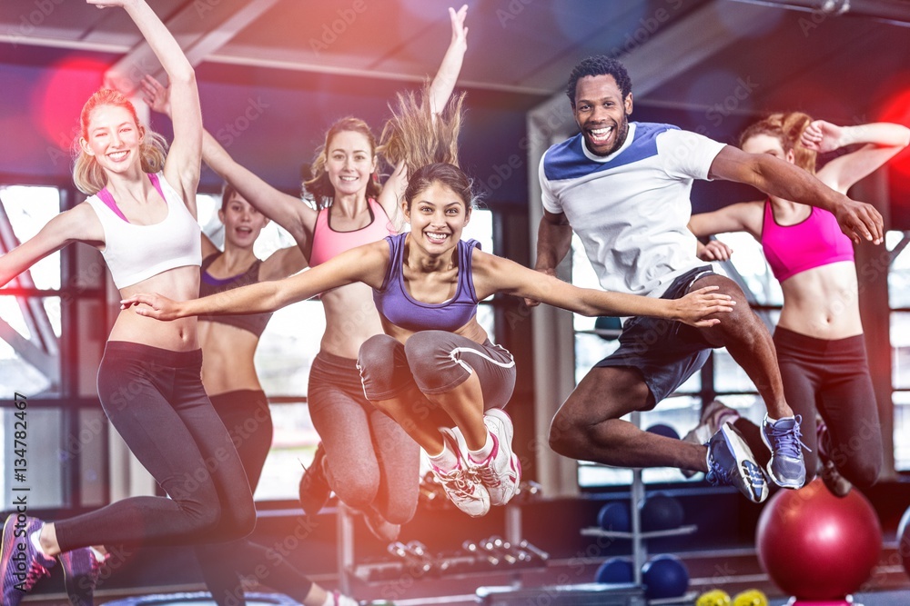 Fit group smiling and jumping - obrazy, fototapety, plakaty 