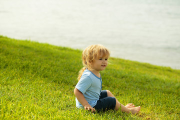 Cute baby boy sits on green grass