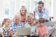 Happy multi-generation family using laptop in living room