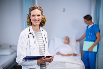 Wall Mural - Portrait of smiling doctor standing with clipboard