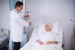 © WavebreakMediaMicro - Doctor adjusting iv drip while patient lying on bed