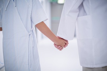 Wall Mural - Doctor and patient holding hands while standing