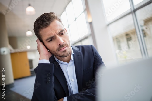 Fotografía Worried businessman sitting at desk with laptop