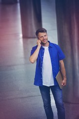 Handsome man holding laptop and talking on mobile phone