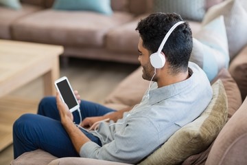 Canvas Print - Man listening to music on mobile phone in living room