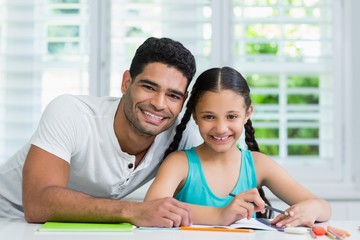 Wall Mural - Father assisting her daughter in doing her homework at home