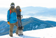 Young Snowboarder Standing Next To Snowboard Thrusted Into Snow With Beautiful Scenery On Background