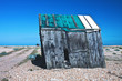 Old slanted wood shack on shingle beach in Dungeness, Kent, England