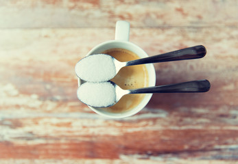 close up of white sugar on teaspoon and coffee cup