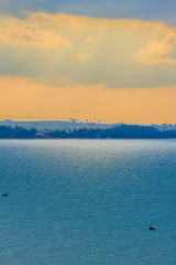 Wall Mural - Beautiful sunrise over the sea in the morning on cloudy day that sun beams break through the clouds. Sun beaming through clouds with urban landscape, if you zoom in will see the small fishing boats.