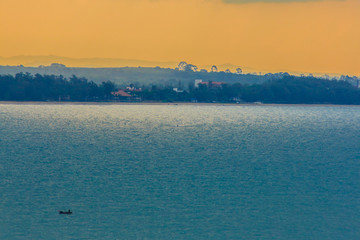 Wall Mural - Beautiful sunrise over the sea in the morning on cloudy day that sun beams break through the clouds. Sun beaming through clouds with urban landscape, if you zoom in will see the small fishing boats.