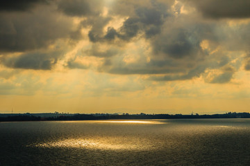 Wall Mural - Beautiful sunrise over the sea in the morning on cloudy day that sun beams break through the clouds. Sun beaming through clouds with urban landscape, if you zoom in will see the small fishing boats.