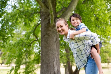 Wall Mural - Mother giving a piggyback ride to his son in park