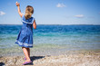 © Sarah Rypma - Girl wearing nautical style dress, throwing pebbles into sea