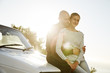 © Westend61 - Young couple in love sitting on car bonnet at backlight