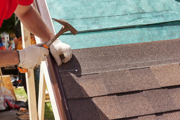 Wall Mural - Roofer builder worker use a hammer for installing roofing shingles