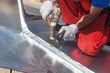 Roofer builder worker finishing folding a metal sheet using rubber mallet