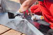 Roofer builder worker finishing folding a metal sheet using rubber mallet