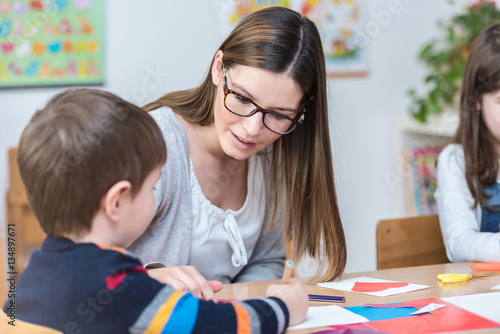 Valokuva Kindergarten Teacher Supports Child on Class