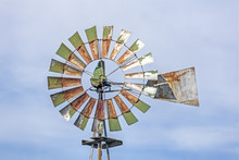 Rusty Green Windmill And Cloudy Blue Sky
