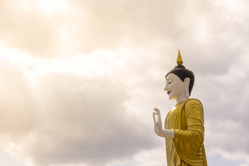 A Standing Buddha Statue on sky background and sunset.