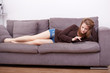 © Stocked House Studio - Happy young woman with tablet pc laying on sofa