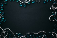 Frame Of Silver Beads And Blue Glass Pebbles On A Black Background