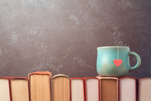 Valentines Day Concept With Tea Cup On Books Over Blackboard Background