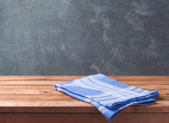 Wall Mural - Empty wooden deck table with blue cheched tablecloth over blackboard background for product montage display