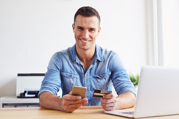 Wall Mural - man sitting in office and pays by credit card