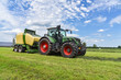Ernte - Traktor mit Rundballenpresse im Einsatz für Grasssilage