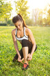 © Bojan - Young woman tying laces of running shoes before training in park.