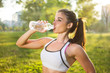 © Bojan - Young smiling woman drinking water from bottle after fitness sport exercise outdoors at sunset.
