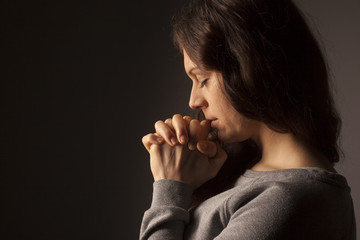 Wall Mural - Praying woman on dark background