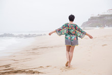 Portrait Of A Happy Mature Woman With Outspread Arms Enjoying Freedom On The Ocean Beach. Freedom Of Travel Vacation. Wellness And Happiness Lifestyle Concept. Portugal. Santa Cruz