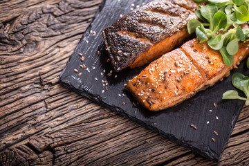 Wall Mural - Salmon fillets. Grilled salmon, sesame seeds herb decorationon on vintage pan or black slate board. fish roasted on an old wooden table.Studio shot.