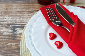 Table setting in white red tone for celebrate St Valentines Day. Plate, cutlery, napkin, gift box with ribbon bow and valentine heart. Love romantic dinner concept. Copy space