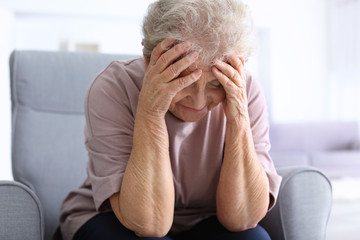 Elderly woman suffering from headache at home