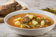 © Sebastian Studio - Bowl of vegetable beef soup with bread and hot chilli peppers in