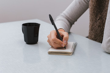 Young woman working at her desk taking notes. Focus on hand writ