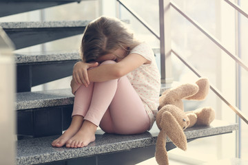 Sad little girl sitting on stairs