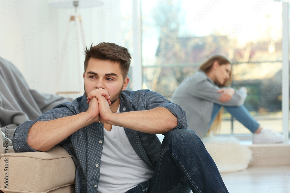 Young sad man after quarrel with girlfriend at home