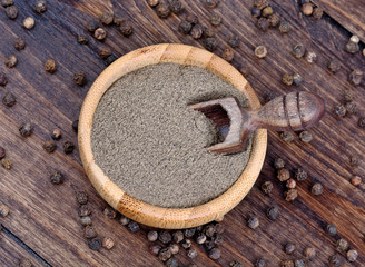 Wall Mural - Bowl with black pepper on wooden background